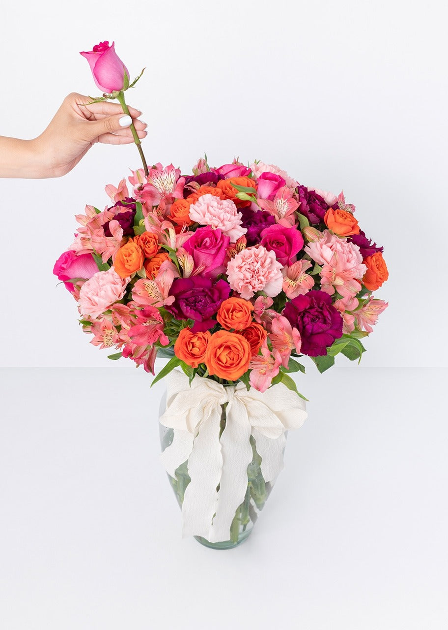 10 rosas naranjas y clavel en jarrón